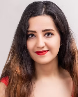 A woman smiling in front of a grey background.
